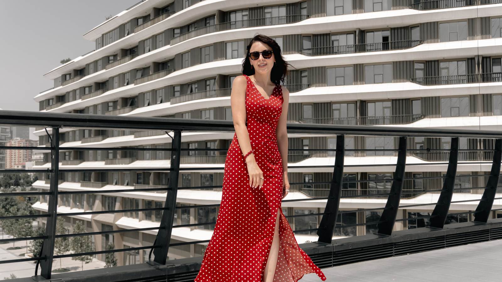 Femme en robe longue rouge à pois marchant sur une passerelle