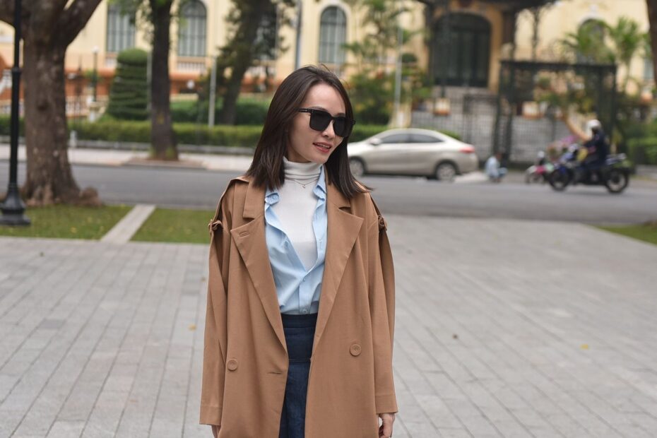 06 t2818 Femme en manteau camel porté sur une chemise bleu clair et un jean, dans la rue