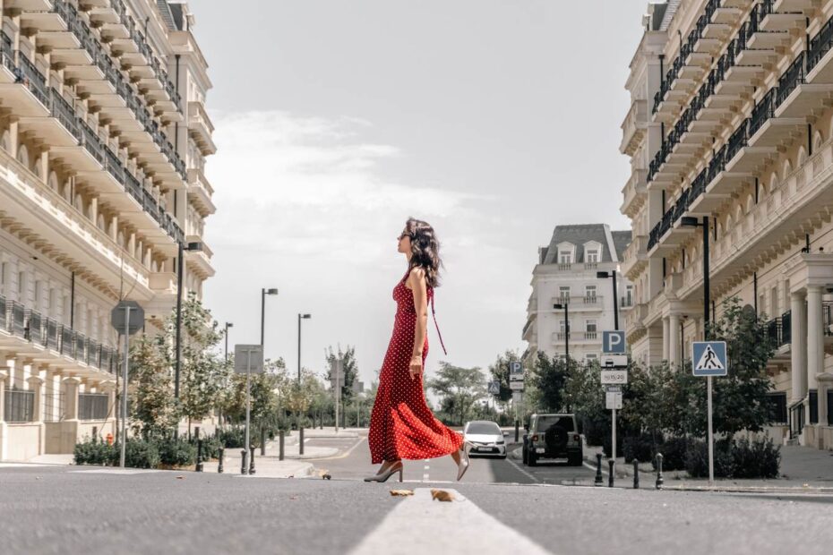 10 rob Femme en robe longue rouge marchant au milieu d'une rue haussmannienne